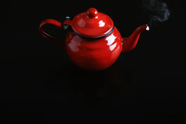 Top view, red enamel coated vintage teapot with hot beverage