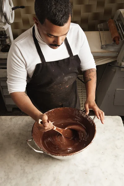 Man twist tasty melted chocolate in big steel pot