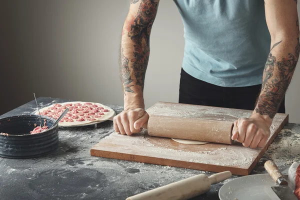 Tattooed chief man cooks pelmeni