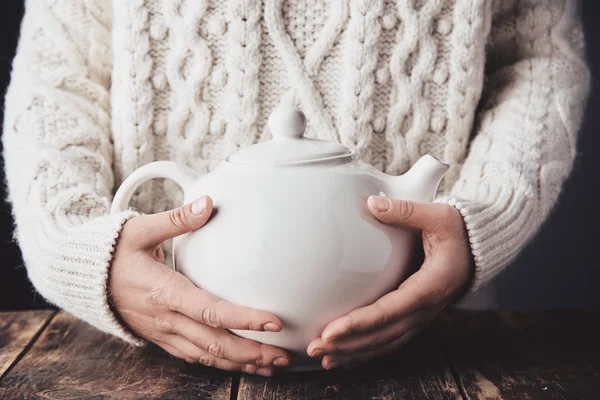 Adult woman hands hug teapot