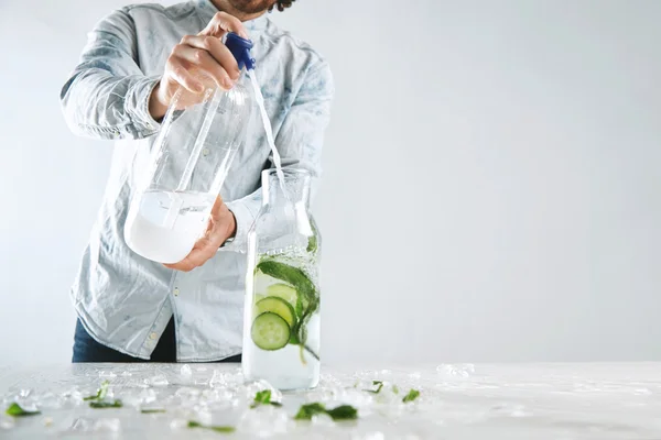 Bartender pours sparkling water in beverage like mojito
