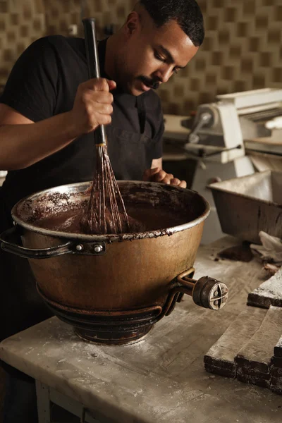 Man cooks, mix melted chocolate with big whisk