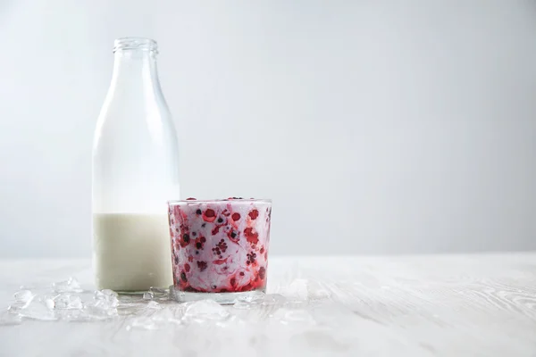 Frozen berries in glass mixed with fresh milk