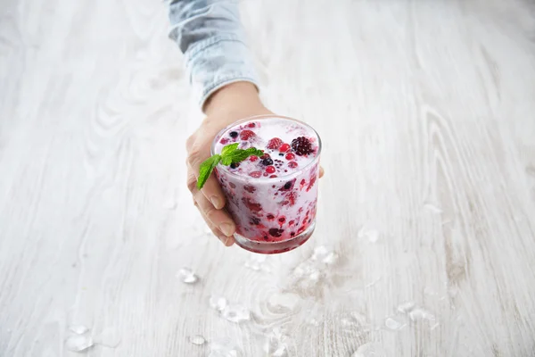 Hand offers frozen berries with milk