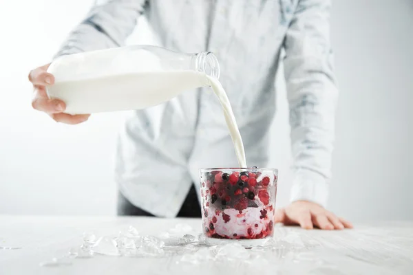 Man pours milk to glass with shake cocktail