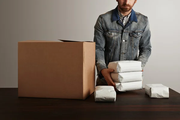 Man puts blank hermetic packages inside big carton box