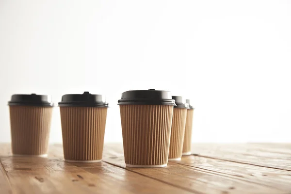 Five carton paper cups with black caps