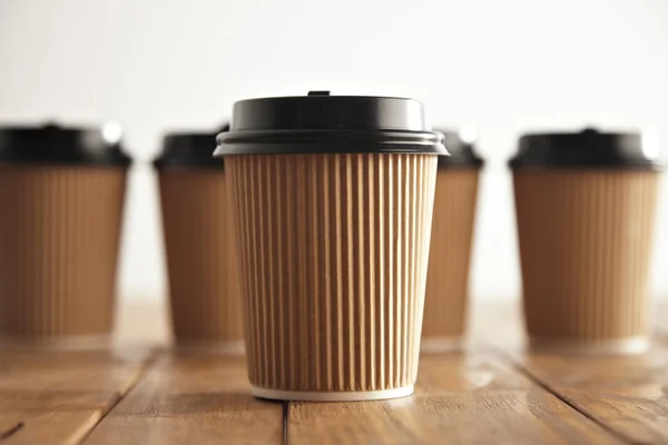 One focused paper coffee cup in front of unfocused others