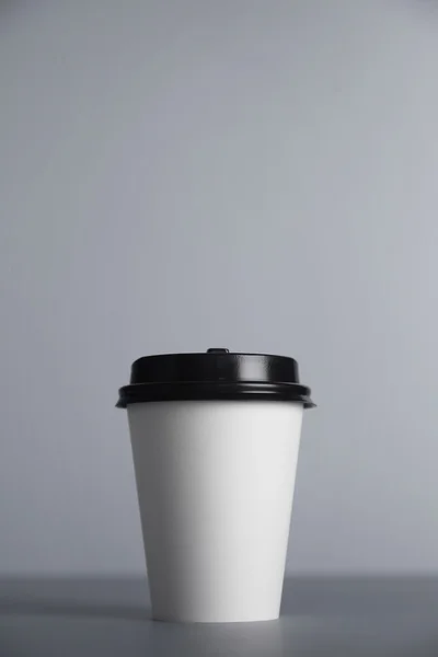 White paper cup with black cap presented in front