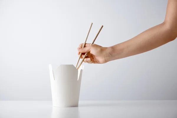 Woman hand uses chopsticks to pick up noodle