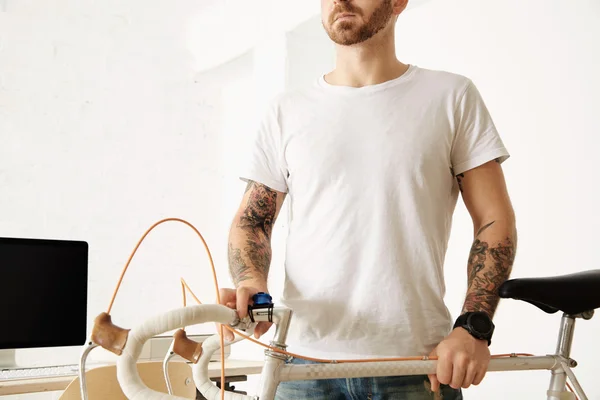 Man in white t-shirt holds vintage bicycle