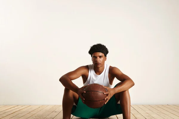 Player holding basketballsitting on floor