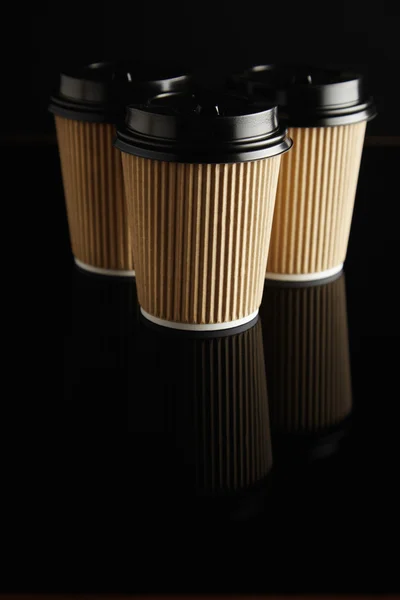 Brown takeaway coffee cups with black lids