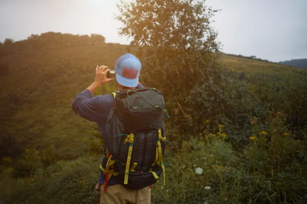 Tourist with backpack walking in grassy hills