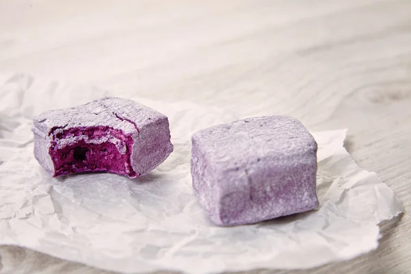 Tasty purple violet pastel marsmallows on craft paper, bite