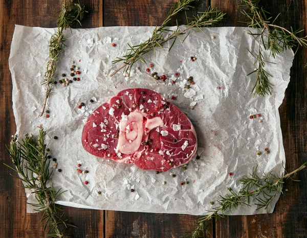 Top view meat steak with bone on craft paper; salted