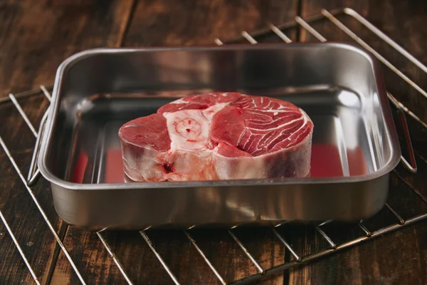 Raw angus leg steak in silver steel pan