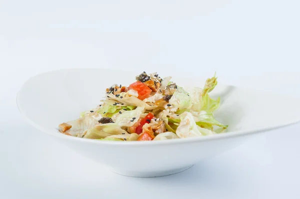 Close up Delisious diet salad with Chinese cabbage, seafood, lettuce, tomatoes, black sesame and soy sauce in a white plate isolated