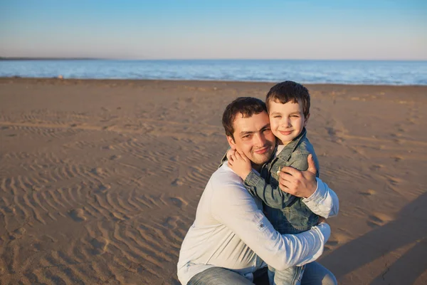 Father hugs his little son and smiles on a beach