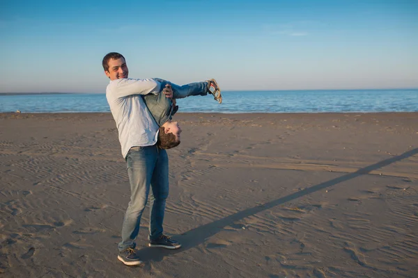 Father holds his little son upside down on a beach