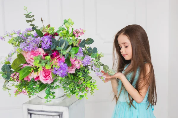 Portrait of pretty little girl near a the flowers in a studio