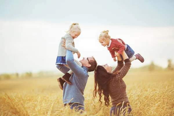 Mother and father holds on a hands their little children on a agricultural field