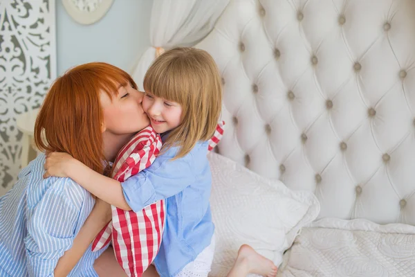 Portrait of mother kisses her little daughter in the morning