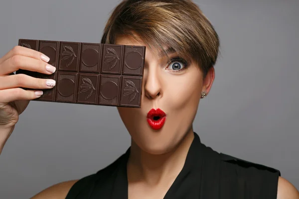 Portrait of a beautiful woman  that is a real chocolate fan on a grey background.
