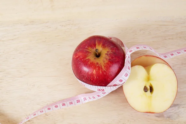 Red apple with centimeter on wood table for diet concept