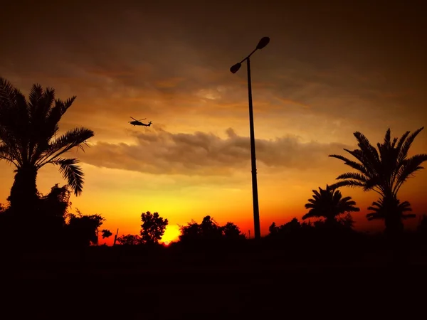 Helicopter in cloudy sky at sunset