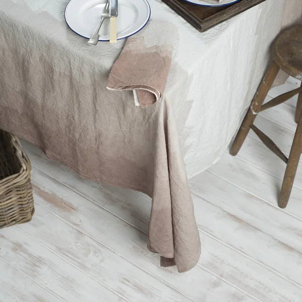 Dinnerware on Table Covered in Gradient Brown Linen Beside Stool