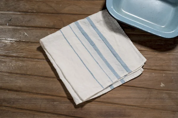 White Dinner Napkin with Blue Bands Alongside Small Empty Tray