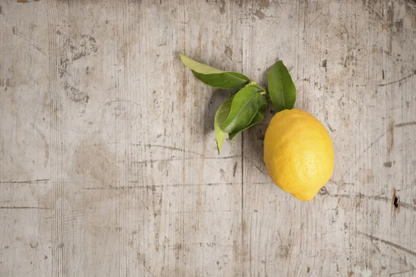 A single lemon and leaves on wood