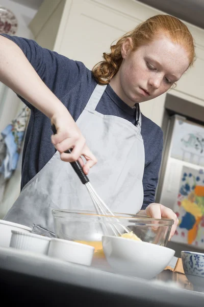 Teenage girl whisking eggs and sugar