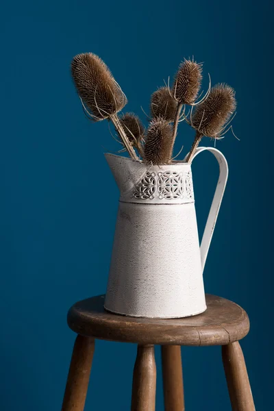 Close Up View of Old Vase with Thistles on Stool