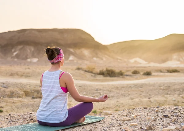 Young woman doing yoga in desert at sunrise time