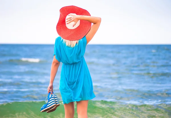 Young pretty woman in red hat relax near blue sea