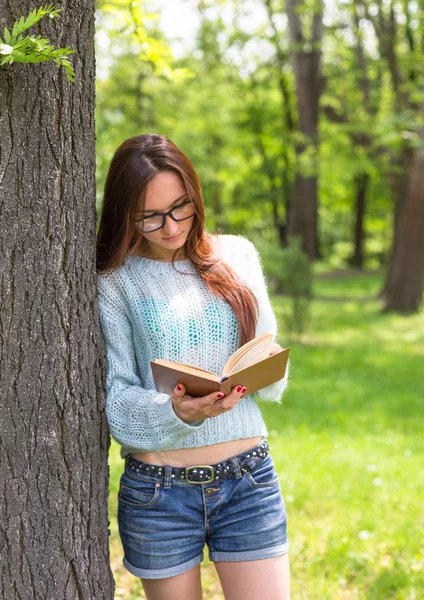 Stylish student girl relax with book in beautiful summer park at sunny day. Outdoor lifestyle picture