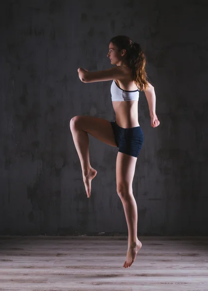 Fitness woman training in dark studio. Young girl posing on black background