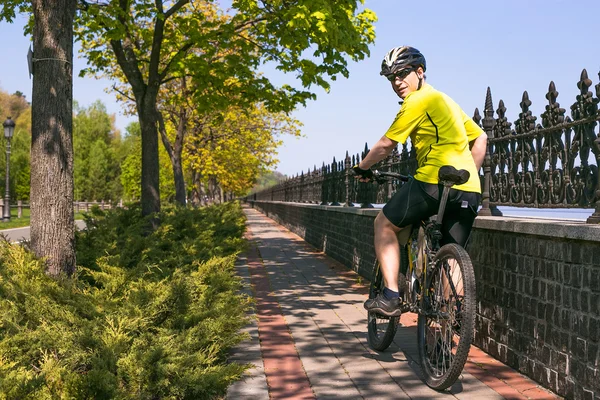 Happy biker ride on road in summer city park. Sport relax concept