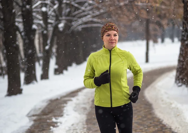 Young sport woman model jogging during winter training outside in winter