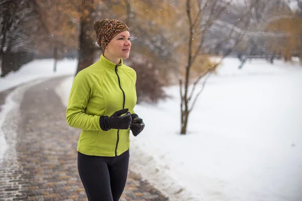 Young sport woman model jogging during winter training outside in winter