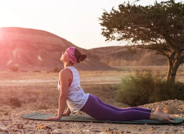 Young woman doing yoga in desert at sunrise time
