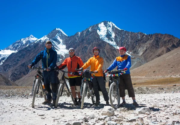 Young happy friends cyclists standing on road in Himalayas mountains