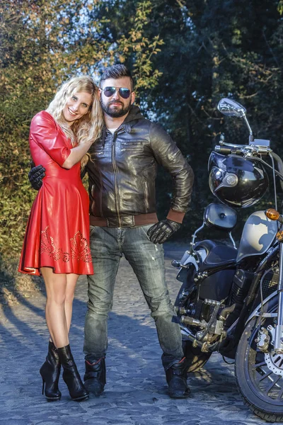 The man on the motorcycle with a sexy young woman in  red dress  the road