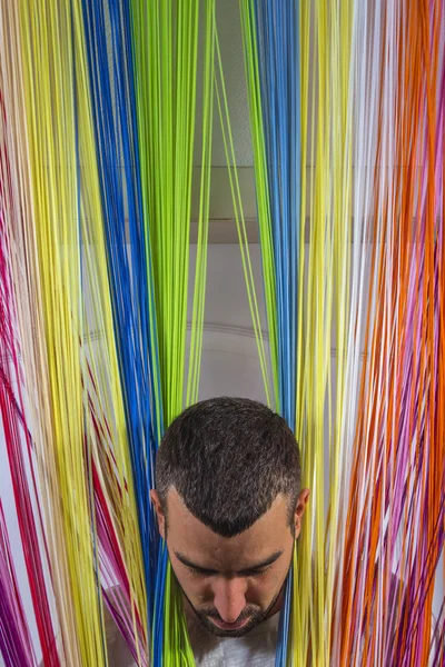 Man peeking his head out of the colored blinds