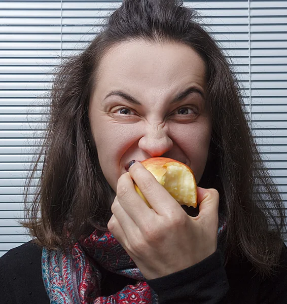 Young beautiful girl eating and biting red apple