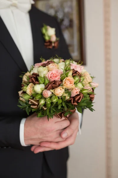 Groom hold wedding bouquet in hand