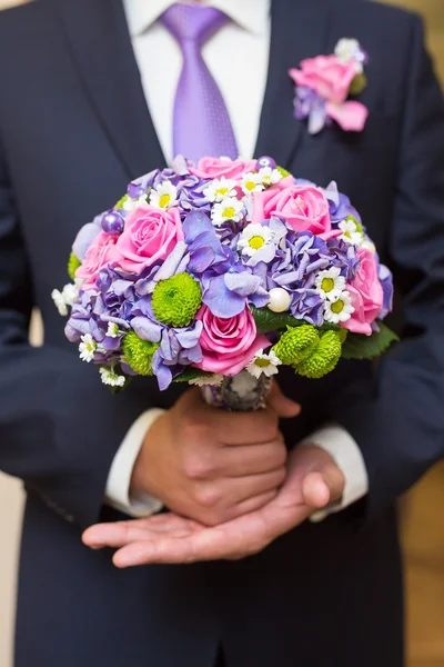 Groom hold wedding bouquet in hand