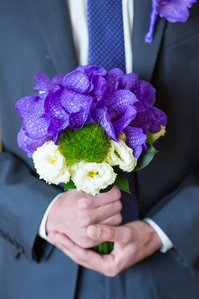 Groom hold wedding bouquet in hand